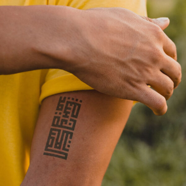 Muscular man with temporary bicep tattoo on arm, Arabic kufic calligraphy text tattoo, silence is a sacred language, semi-permanent tattoo, removable halal black jagua henna tattoo