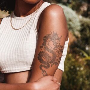 Large dragon semi-permanent tattoo on girl's arm, removable halal black jagua henna tattoo on dark skin